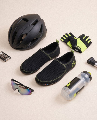 Black slip-on athletic shoes with mesh design, shown with cycling gear on beige background