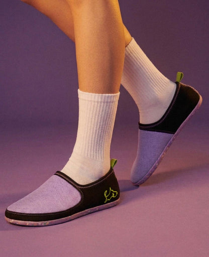 Lightweight purple slip-on shoes with black trim, worn with white socks on a purple background