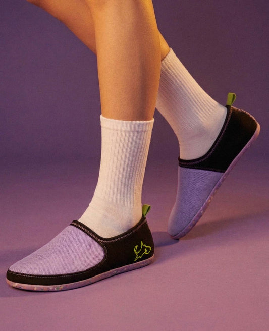 Lightweight purple slip-on shoes with black trim, worn with white socks on a purple background