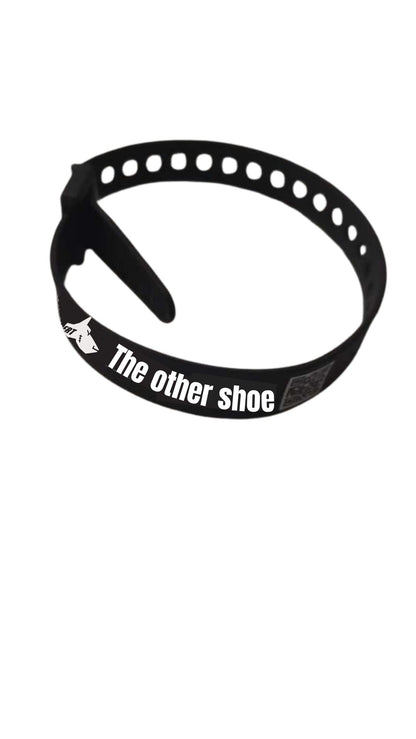 Black adjustable shoe strap with 'The other shoe' text, lightweight and minimalist design.