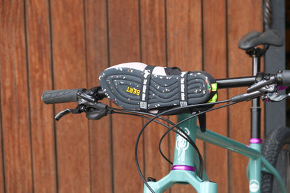 Lightweight slip-on shoe with speckled sole strapped to bike handlebars, wooden background.