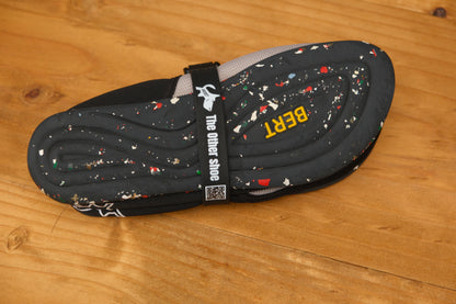 Lightweight slip-on shoe with speckled black sole and 'BERT' text, shown on wooden surface